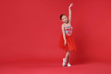 Kırmızı arka planda dans eden tatlı küçük kız, mesaj için yer.