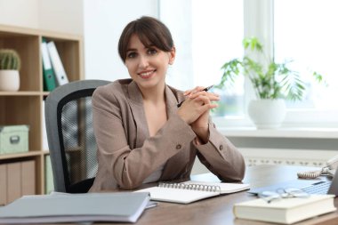 Portrait of smiling secretary at table in office