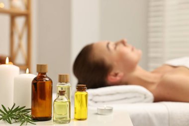 Aromaterapi. Spa salonundaki masaj koltuğunda dinlenen kadın, gerekli yağlar, yanan mumlar ve biberiye şişelerine odaklanıyor.