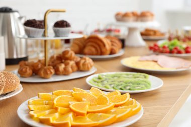 Kapalı alanda, ahşap masada farklı yemekler servis ediliyor. Açık büfe menüsü