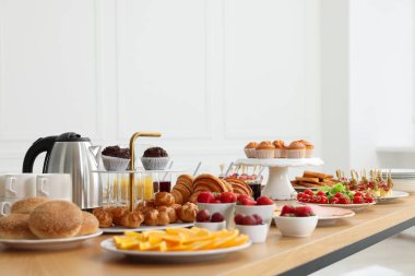 Kapalı alanda, ahşap masada farklı yemekler servis ediliyor. Açık büfe menüsü