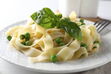 Delicious pasta with green peas served on white table, closeup