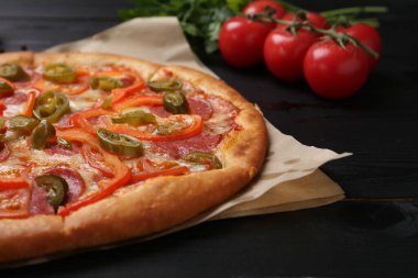 Lezzetli pizza Diablo ve siyah ahşap masa malzemeleri, yakın plan.