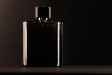 Luxury men`s perfume in bottle on table against dark background, space for text