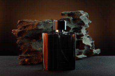 Luxury men`s perfume in bottle on grey table against brown background