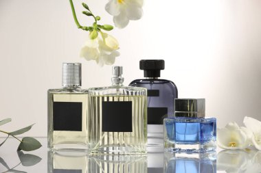 Ayna yüzeyinde açık gri arkaplana karşı lüks parfümler ve çiçek dekoru