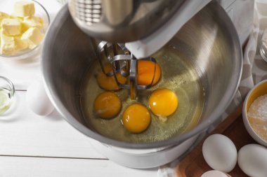 Para kazanmak. Beyaz masadaki karıştırıcı kasesinde çiğ yumurta, yakın plan.