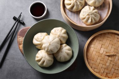 Lezzetli bao çörekleri (baozi), yemek çubukları ve soya sosu gri masada, düz yatıyordu.