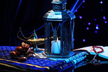 Arap feneri, Kur 'an, Misbaha, Aladdin sihirli lamba, hurmalar ve katlanmış secdeler gece bulanık ışıklara karşı ayna yüzeyinde