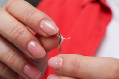 Kadın iğne deliğinden iplik sokuyor, yakın plan.