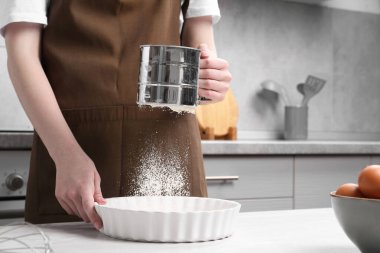 Mutfaktaki masada un süzen kadın, yakın plan.