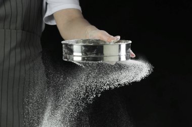 Masada siyah arka planda un süzen kadın, yakın plan.