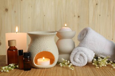 Aromaterapi. Kokulu mumlar, şişeler, çiçekler ve havlular bambu hasırında