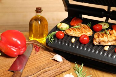 Electric grill with different products and knife on table