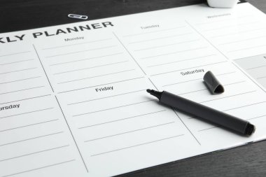 Zaman çizelgesi. Haftalık planlamacı ve siyah ahşap masadaki kalemi hissetti.