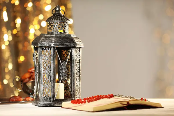 stock image Arabic lantern, Quran, misbaha and dates on table against blurred lights, space for text