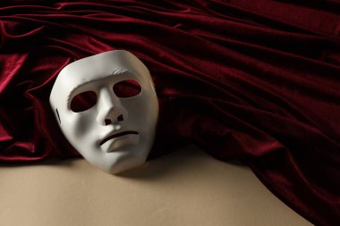 Tiyatro sanatları. Beyaz maske ve bej arkaplanda kırmızı kumaş