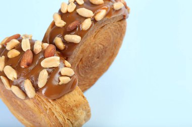 Lezzetli puf böreği. Çikolata ezmeli ve fındıklı üstün kruvasanlar açık mavi arka planda, yakın plan. Metin için boşluk