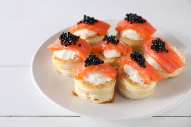 Krem peynirli lezzetli puf böreği, somon balığı ve beyaz ahşap masada siyah havyar.