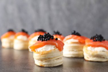 Krem peynirli lezzetli puf böreği, somon balığı ve gri masada siyah havyar.