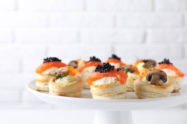 Different delicious puff pastry snacks on stand clipart