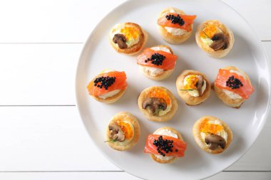 Beyaz ahşap masada farklı lezzetli hamur işi atıştırmalıklar, üst manzara.