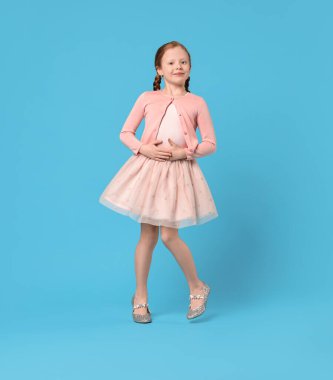 Açık mavi arka planda dans eden tatlı küçük kız.