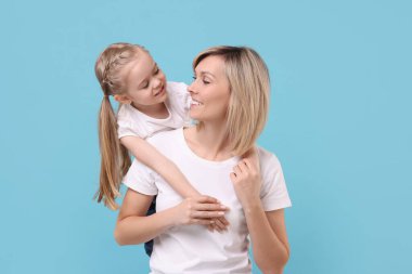 Family portrait of happy mother and daughter on light blue background