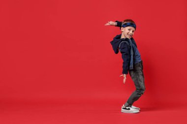 Kırmızı arka planda dans eden mutlu küçük çocuk. Metin için boşluk