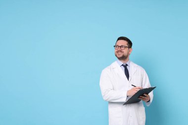 Açık mavi zemin üzerinde kalem ve pano ile gülümseyen doktor, metin için boşluk