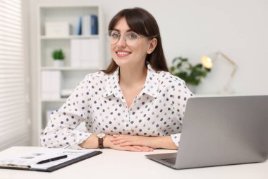 Portrait of smiling secretary at table in office