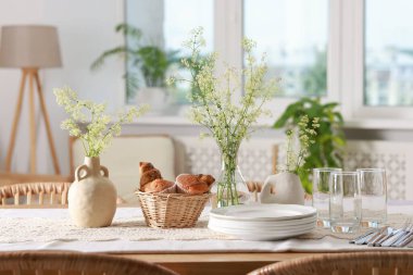 Şık yemek odasındaki temiz tabaklar, çiçekler ve taze hamur işleri.