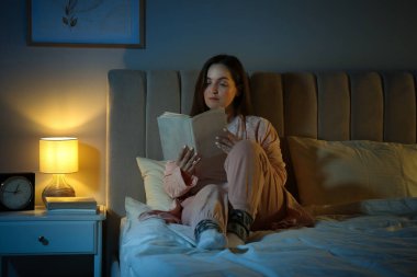 Güzel kadın gece yatmadan önce kitap okuyor.