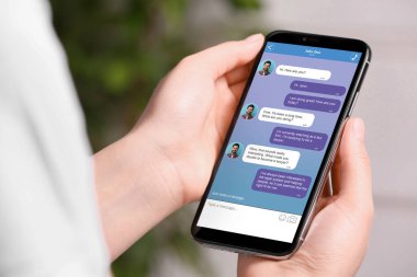 Dışarıda cep telefonuyla mesajlaşan bir kadın, yakın çekim. İletili aygıt ekranı