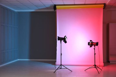 Modern stüdyoda neon ışıkları ve profesyonel ışıklandırma ekipmanları için fotoğraf arkaplanı, metin için alan
