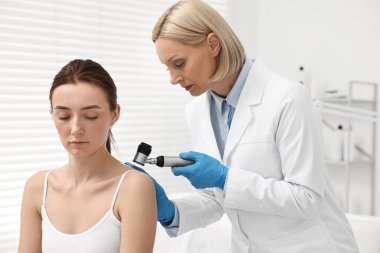 Dermatoskoplu bir dermatolog klinikteki hastayı muayene ediyor.