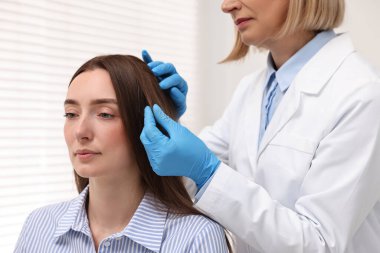 Trikoloğum klinikte hastanın saçını inceliyor.