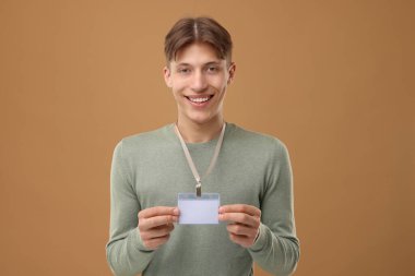 Happy man with blank badge on light brown background