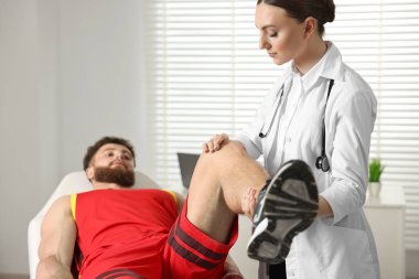 Spor sakatlığı. Hastanede hastanın bacağını muayene eden doktor.