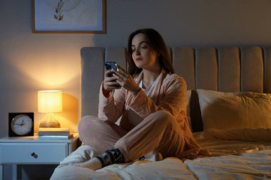 Woman using smartphone on bed at night. Internet addiction