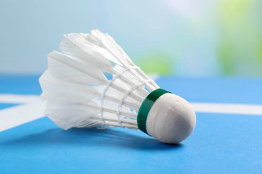 Tüylü badminton mekik horozu mavi masada bulanık arka planda, yakın plan