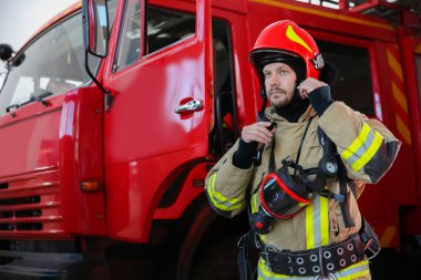 Firefighter in uniform near red fire truck at station