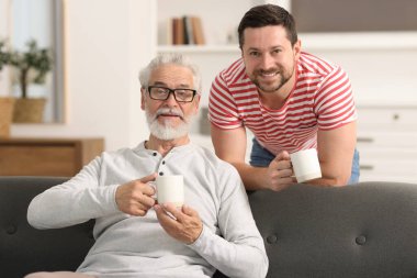 Mutlu oğul ve babası evde fincanlarla