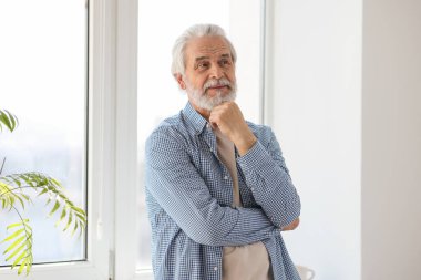 Pencerenin yanında gri saçlı mutlu büyükbabanın portresi.
