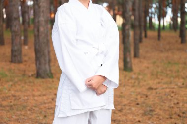 Kimonolu tatlı küçük kız ormanda karate yapıyor, yakın plan.