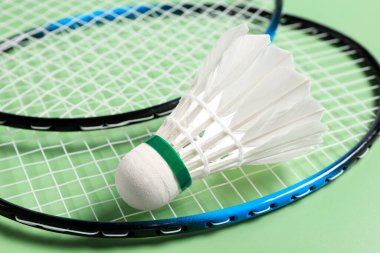 Tüylü badminton mekiği ve raketleri yeşil arka planda yakın plan