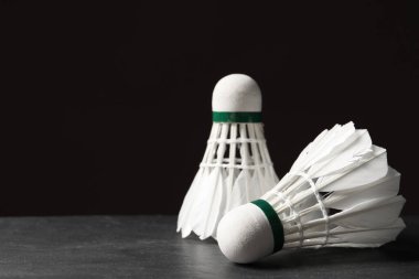 Tüylü badminton mekikleri siyah arka plana karşı gri masada, yakın plan. Metin için boşluk
