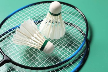 Tüylü badminton mekikleri ve raketleri yeşil arka planda yakın plan