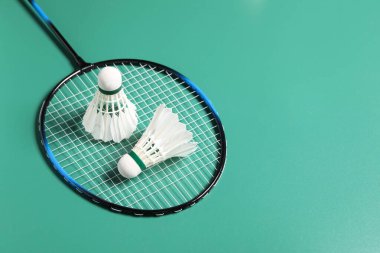Badminton mekikleri ve raketleri yeşil arka planda tut. Metin için boşluk
