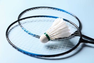 Tüy badminton mekik horozu ve açık mavi arka planda raketler, yakın plan